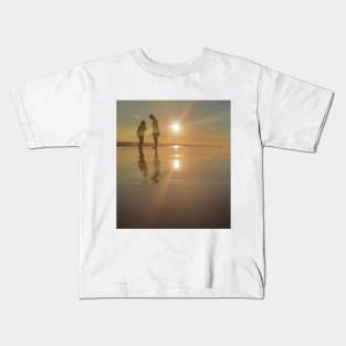 Silhouetted people in a row on a sand beach. Kids T-Shirt